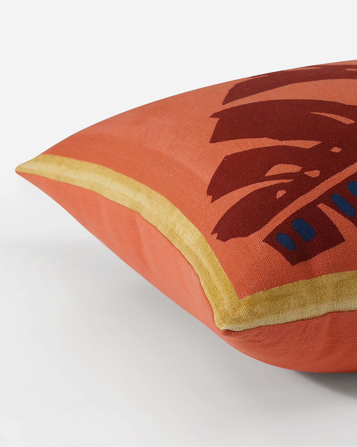 Orange throw pillow corner detail with brown leaf motif and blue dots