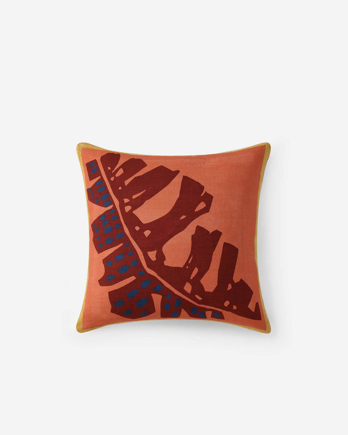 Orange throw pillow with brown leaf sketch and blue dotted accents