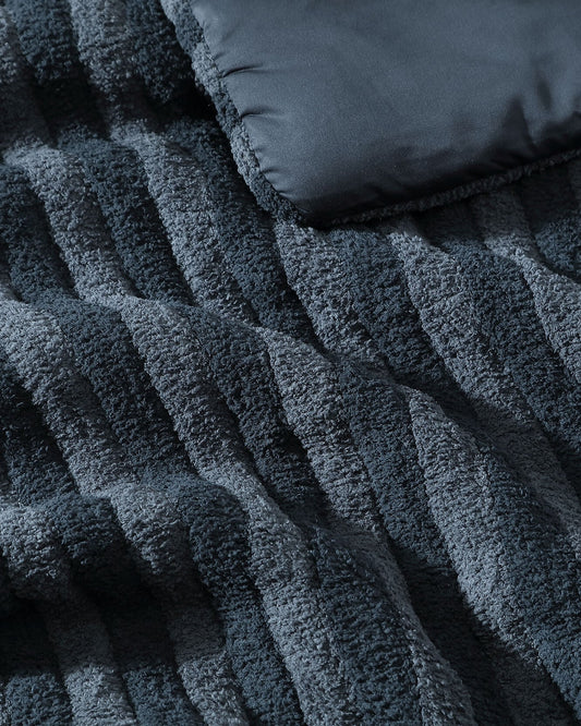 Piped comforter fabric close-up, dark blue ribbed quilt texture with raised lines