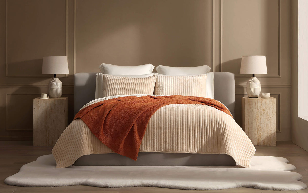 Rust velvet channel quilt on bed, smooth raised stripes and neatly stitched edges