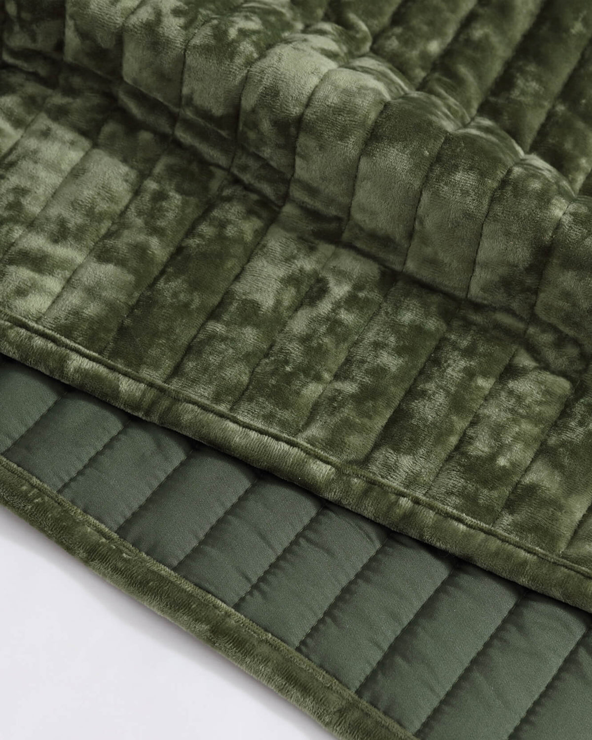 Olive green velvet quilt close-up showing raised channel stripes and stitched edges.