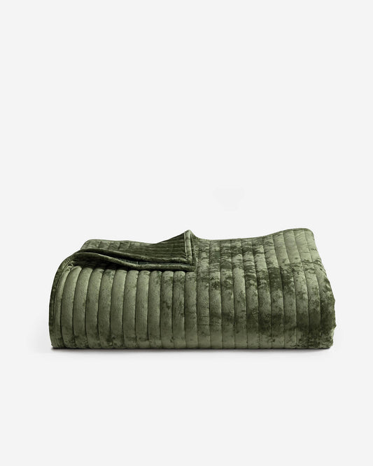 Olive green velvet quilt with stitched channel stripes and folded edge detail.