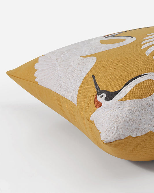 Gold throw pillow corner with large white crane embroidery detail