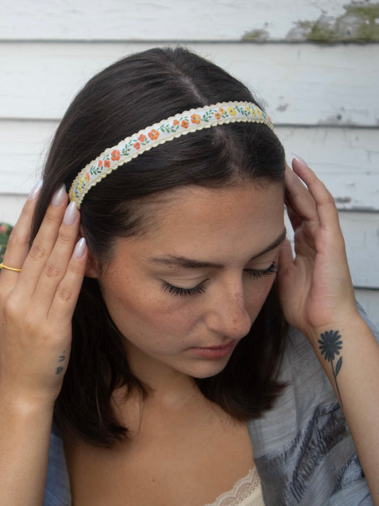 Skinny headband with multicolor floral trim, worn across dark hair