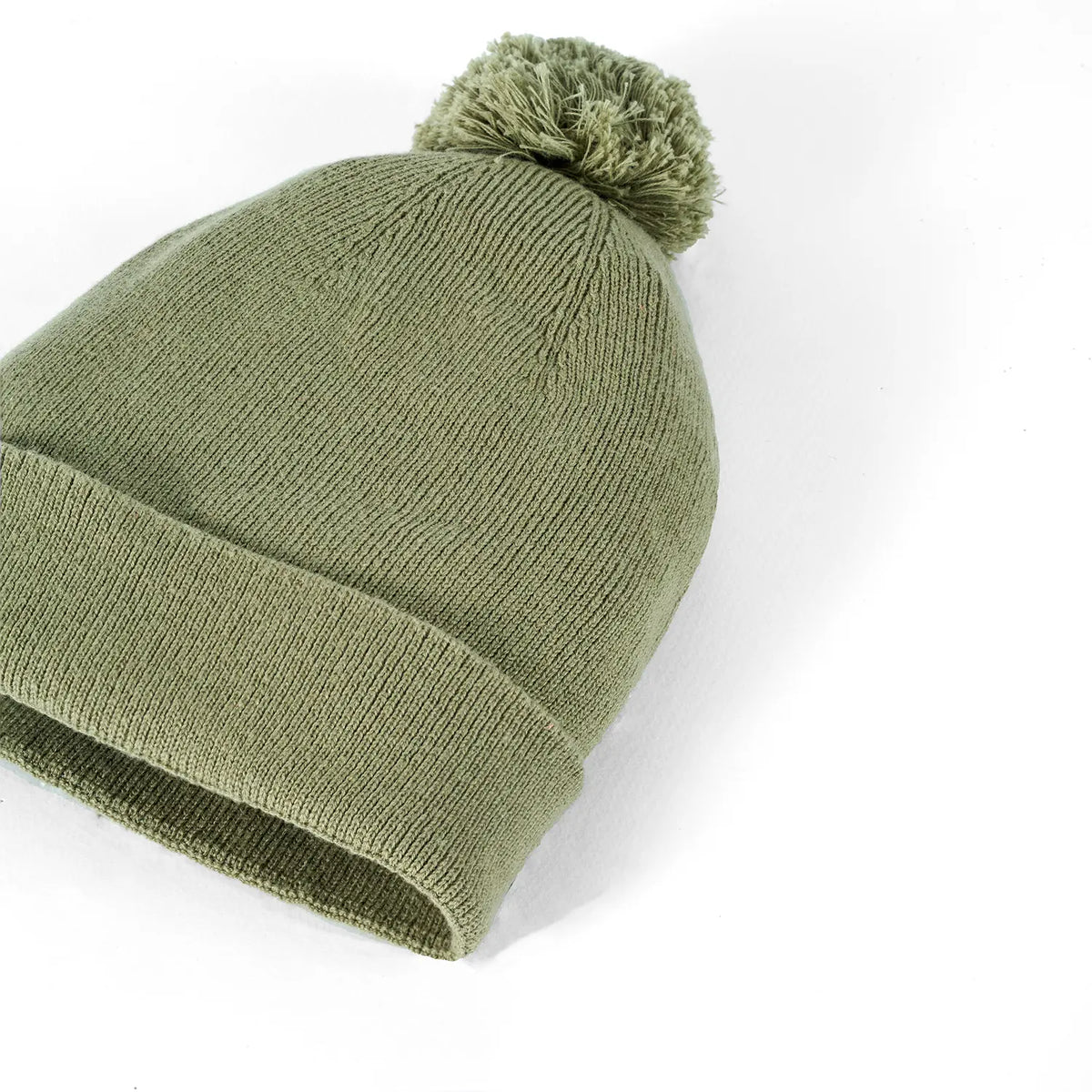 Sage green knit baby beanie with pom-pom and ribbed cuff.
