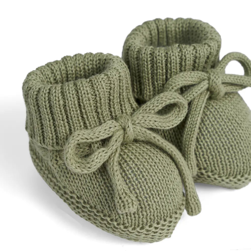 Sage green knitted baby booties with bow ties and ribbed cuffs, close-up pair