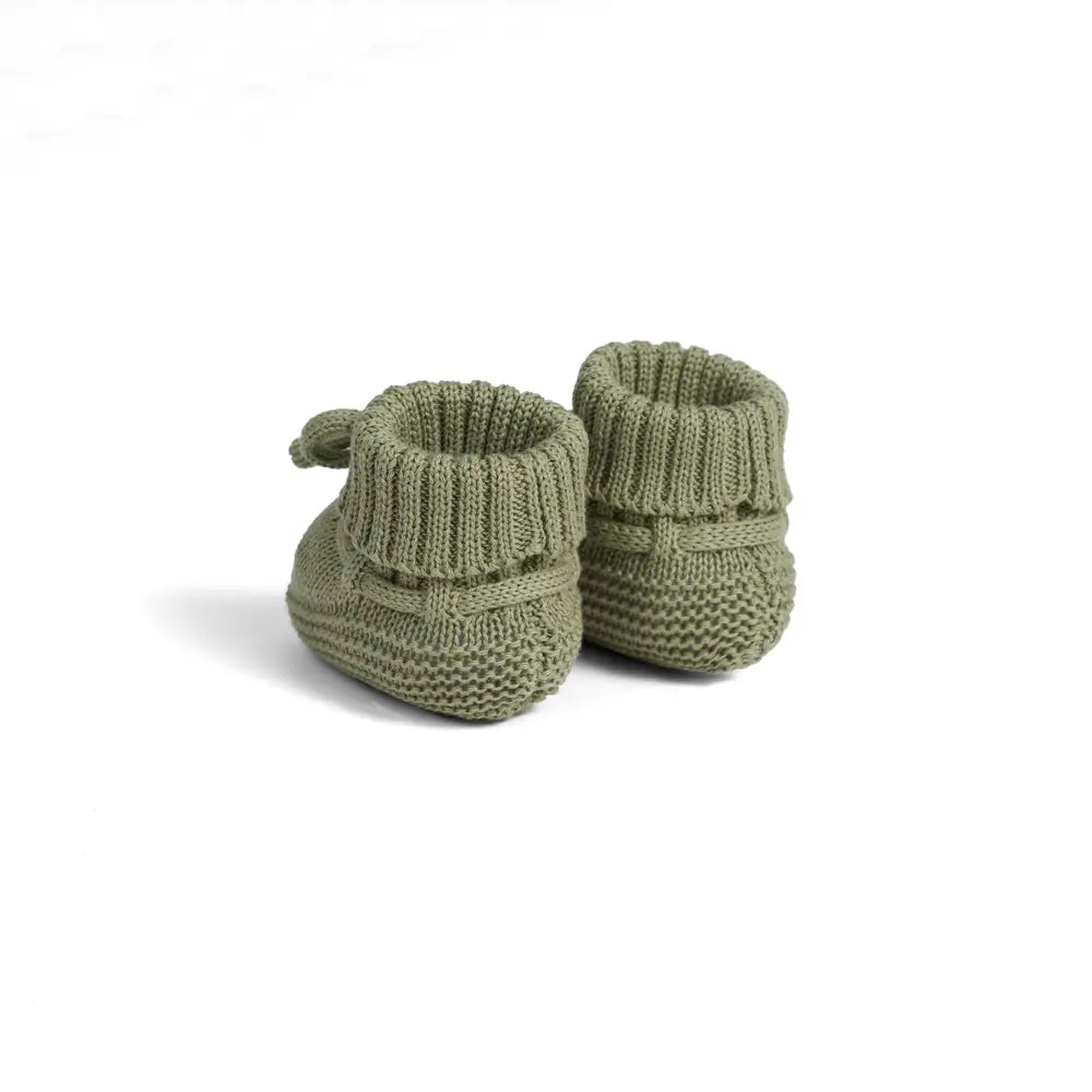 Sage green knitted baby booties with ribbed cuffs and bow ties, side view pair