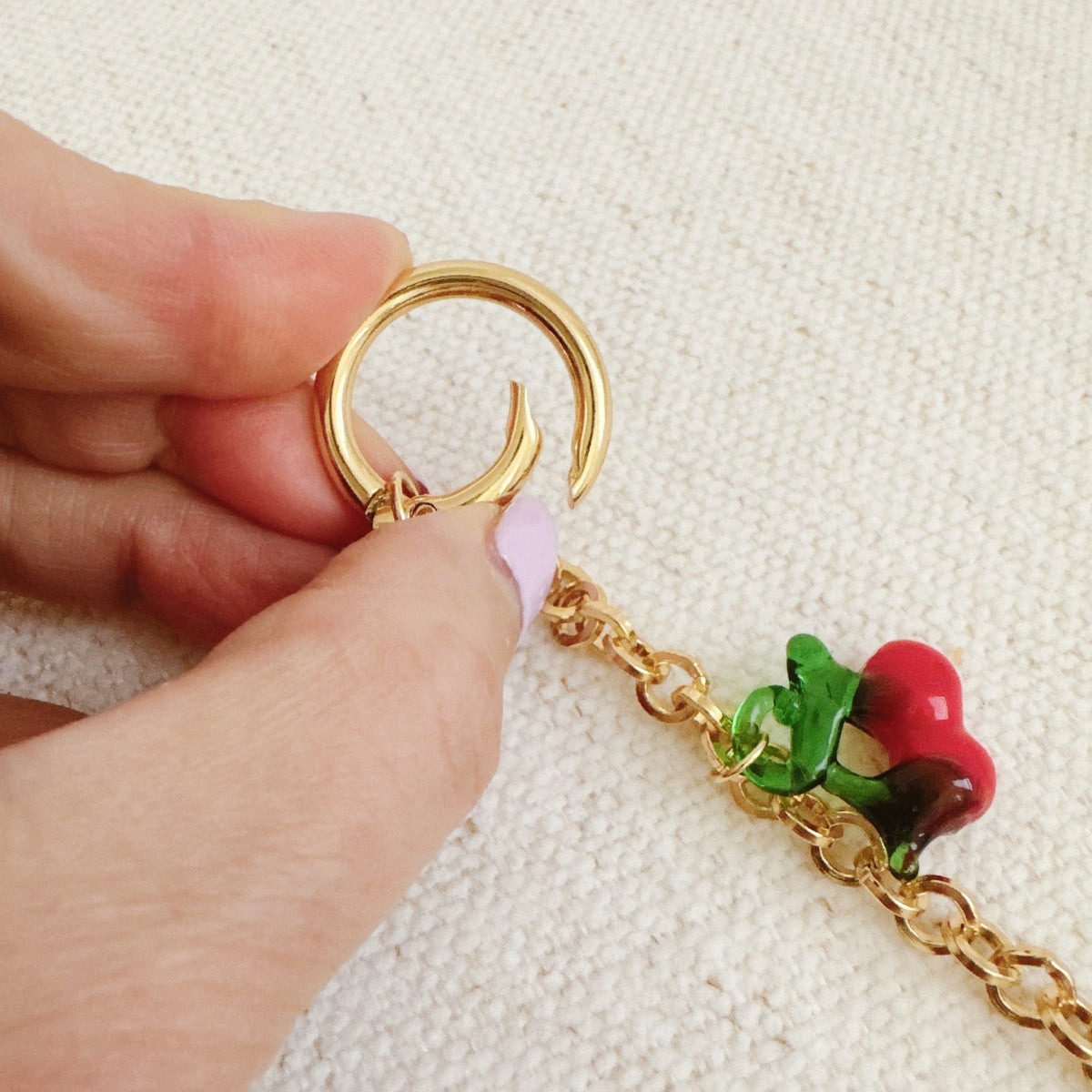 Gold ring bag charm clasp with small red and green cherry drop charm