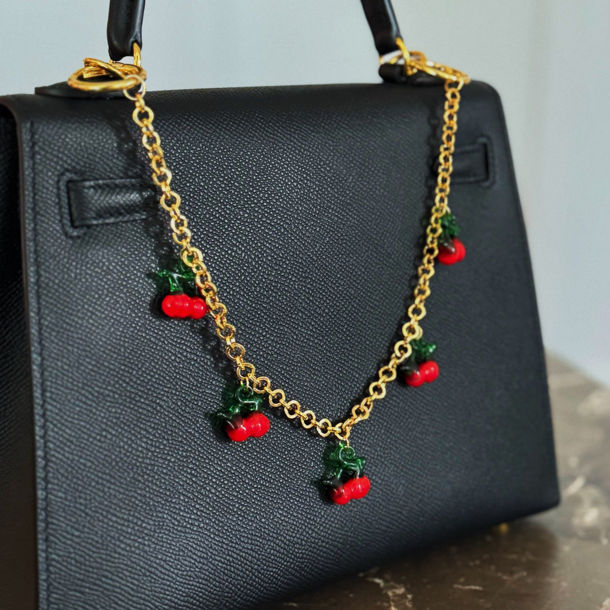 Gold chain bag charm with red cherry drops and green leaves