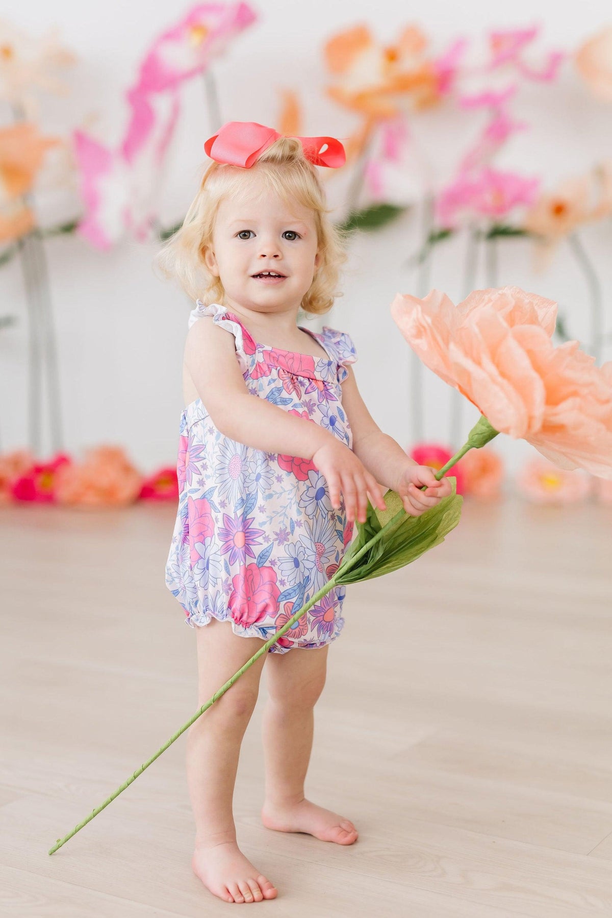 Pastel floral ruffle romper with cross-back straps and short gathered legs