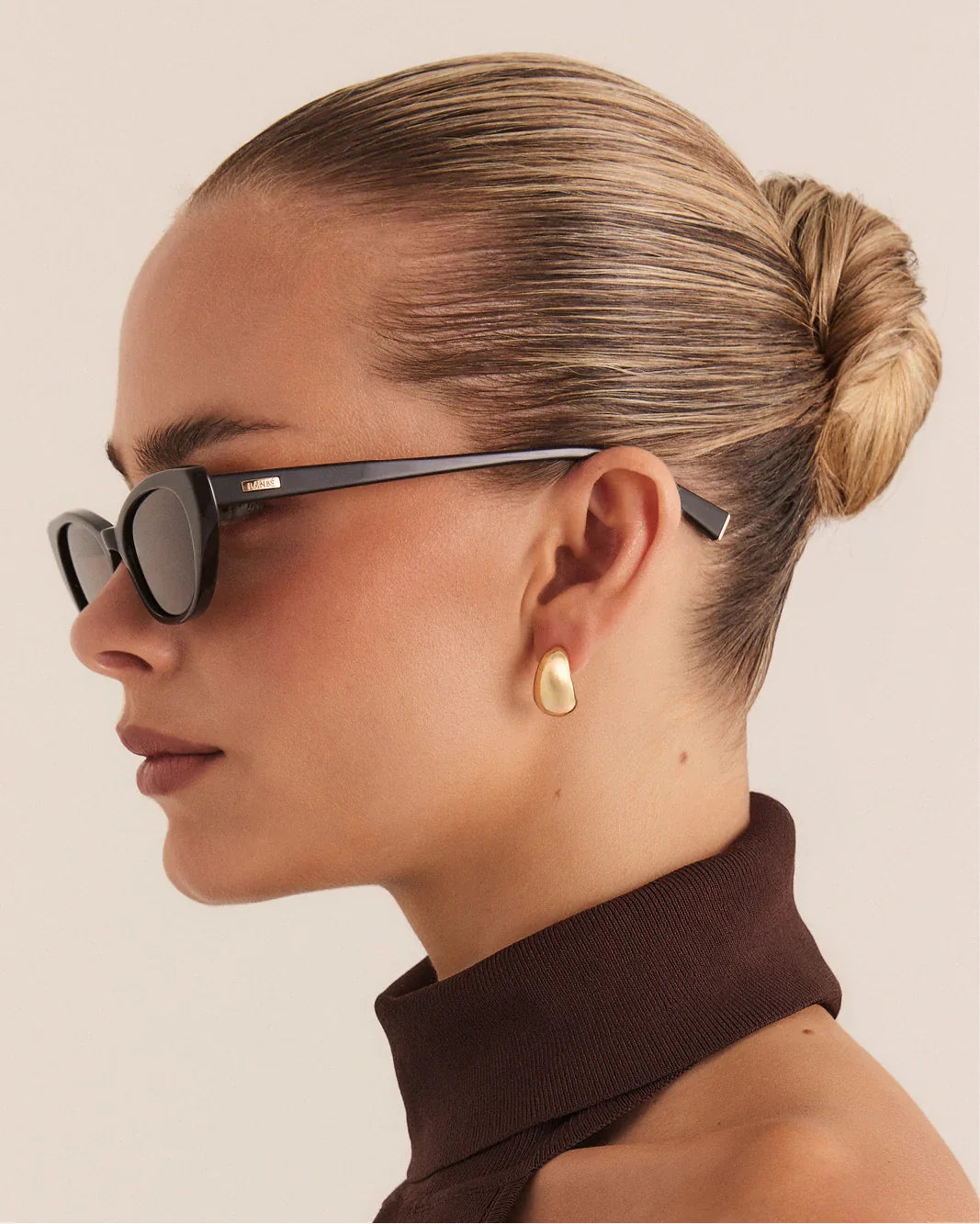 Side profile cat-eye sunglasses with dark frame and tinted brown lenses