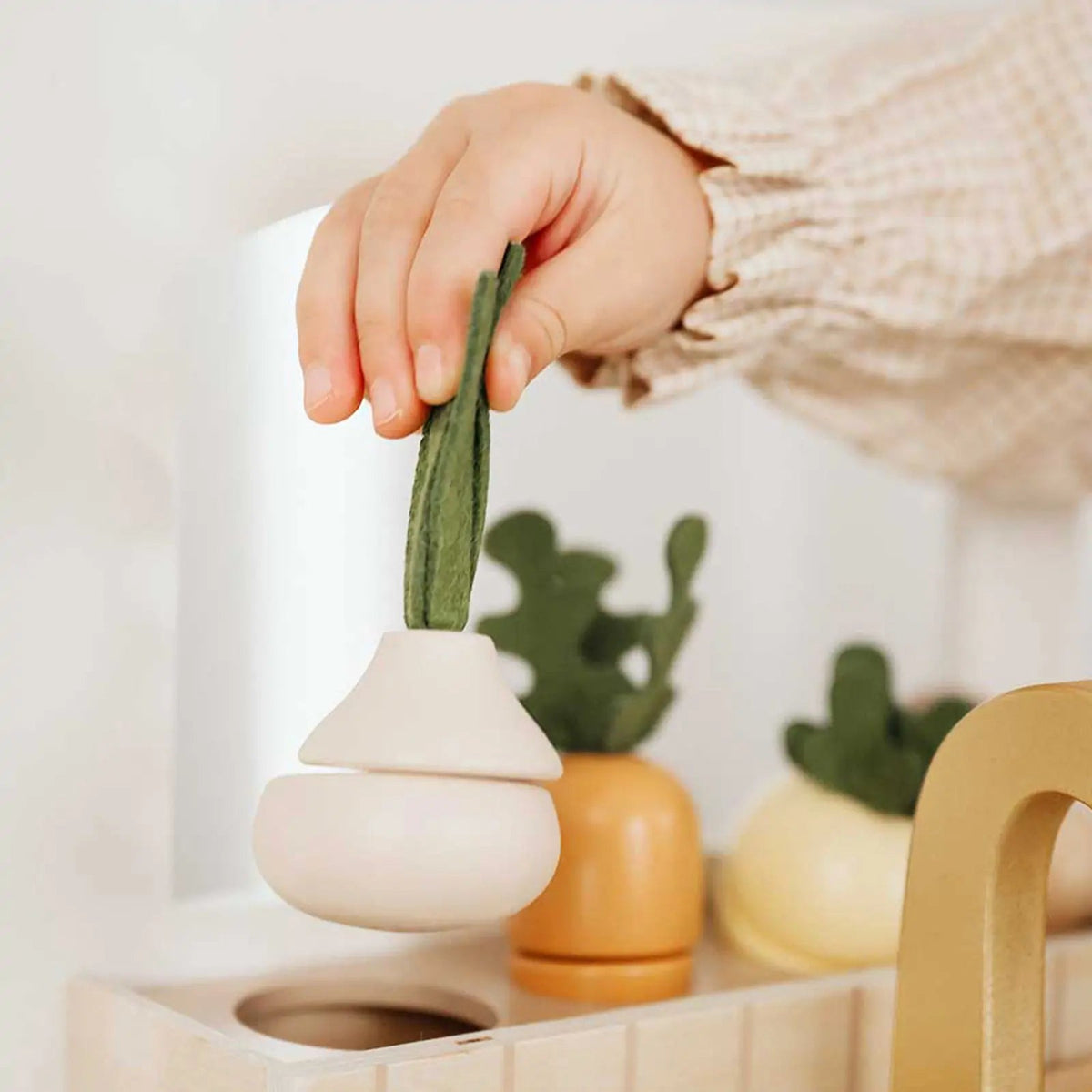 Wooden play kitchen with toy pot and gold faucet beside the sink