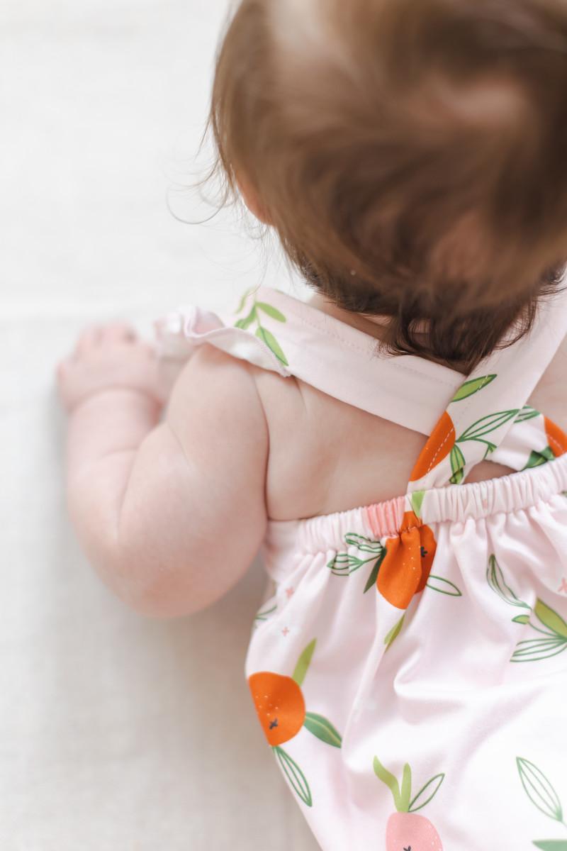 Baby romper back detail with ruffle straps and fruit-print fabric