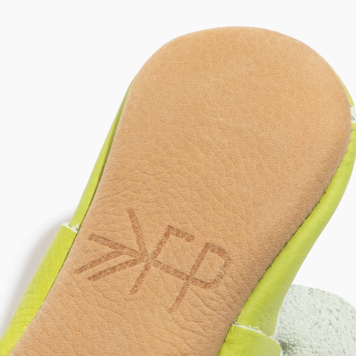 Lime green baby shoe insole close-up with FP logo embossing