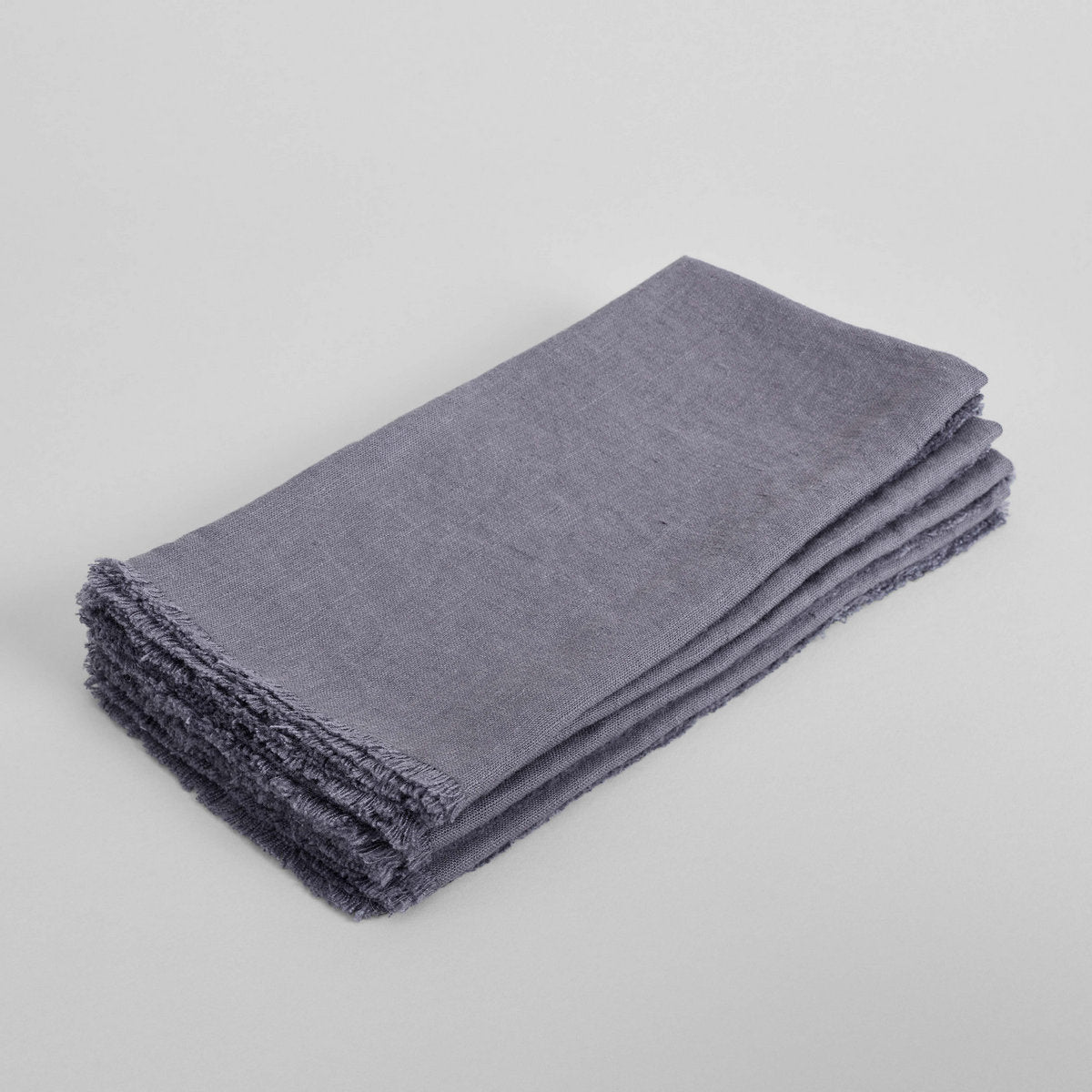 Dark grey linen napkin, folded with frayed fringe along the edges