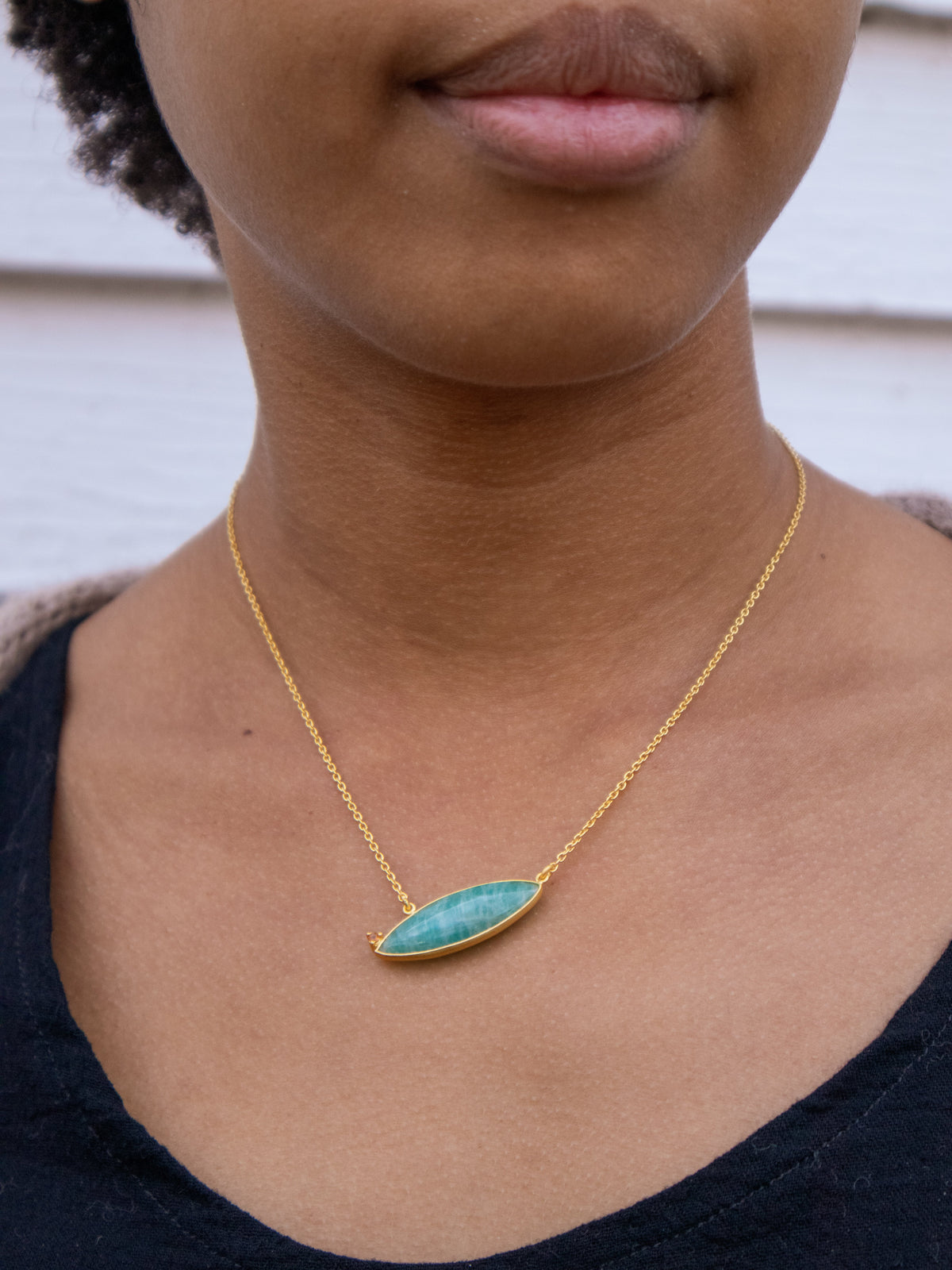 Gold chain necklace with oval blue-teal stone pendant close-up