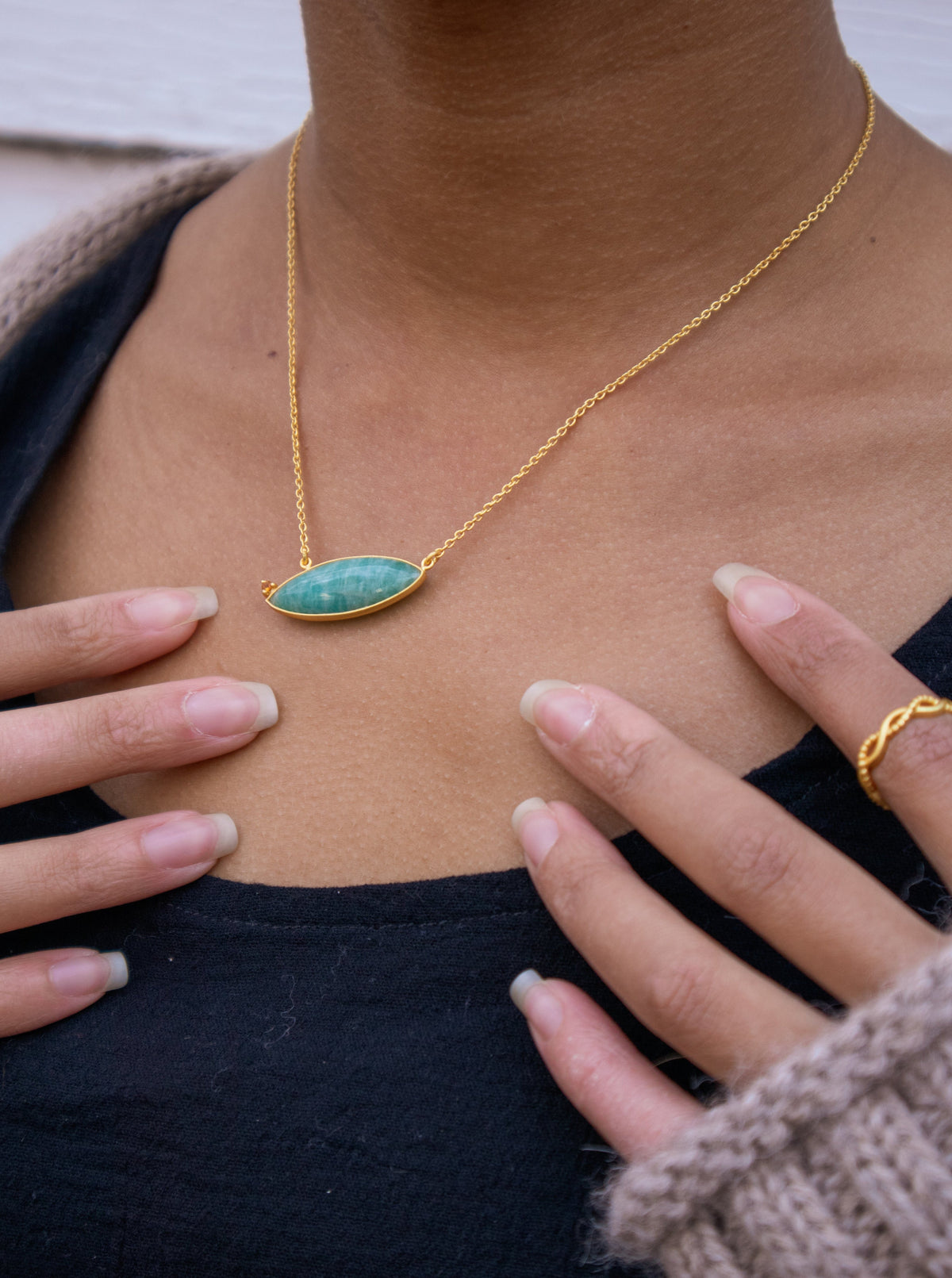 Gold chain necklace with oval blue-teal stone pendant on neck
