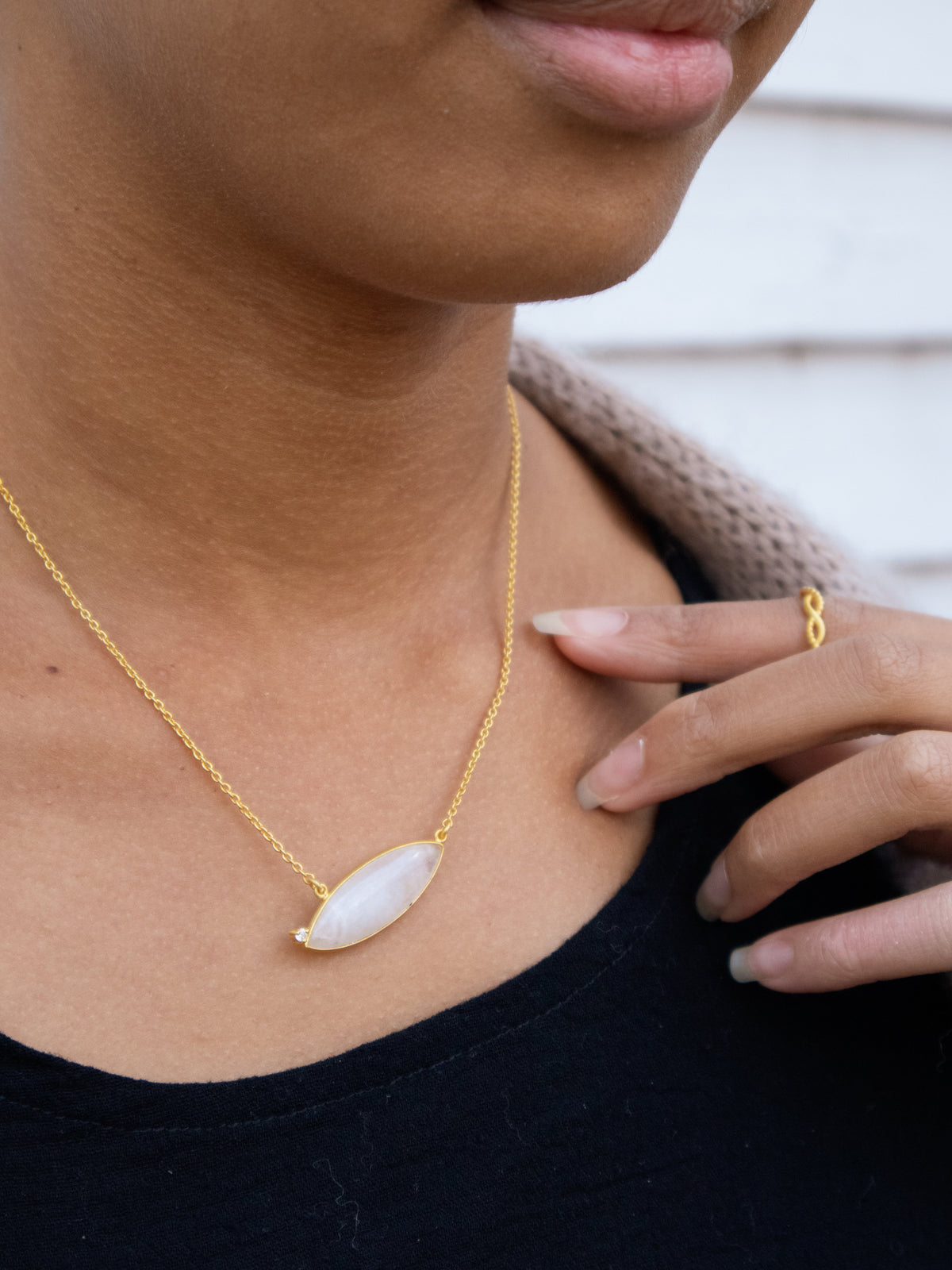 Gold chain necklace with oval white gemstone pendant, close-up view