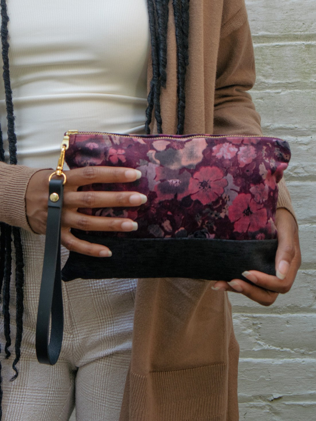 Velvet wristlet front view with purple floral top and black base, gold zipper edge.