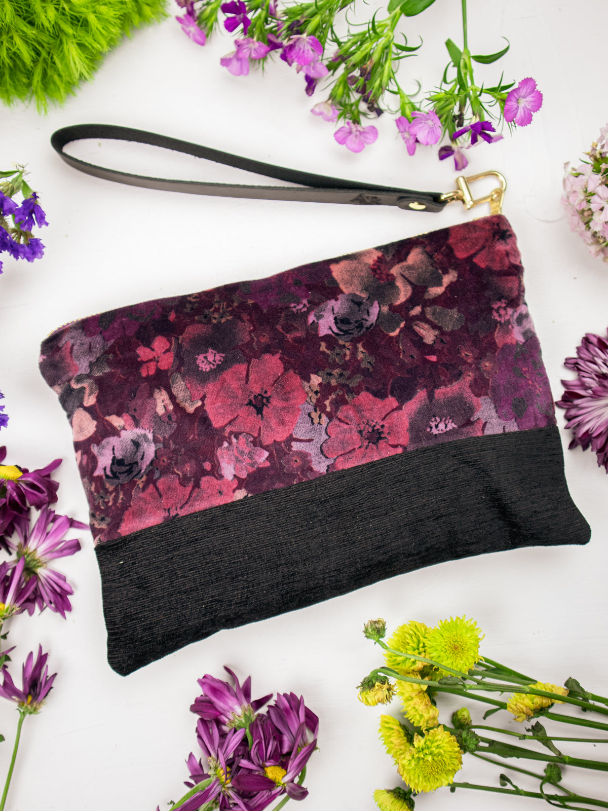 Velvet wristlet with purple floral velvet body, black bottom, gold zipper, wrist strap.