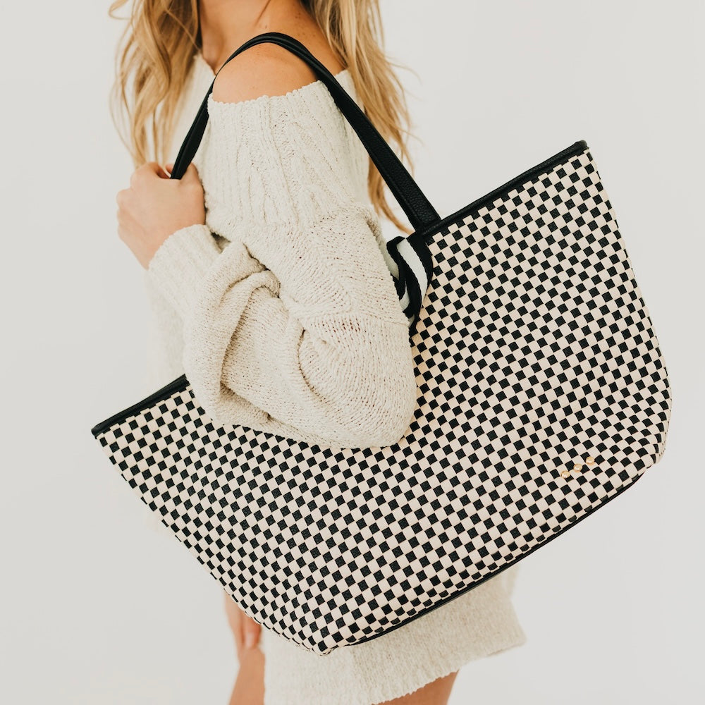 Woven checkered tote bag with black and white pattern and black top handles
