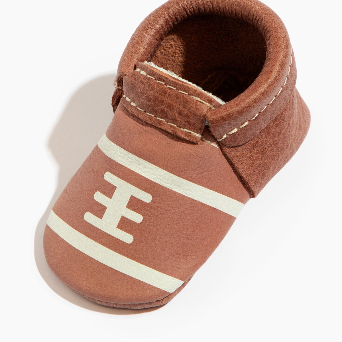 Brown baby soft-sole shoe with H-logo stripe and stitched collar, angled close-up