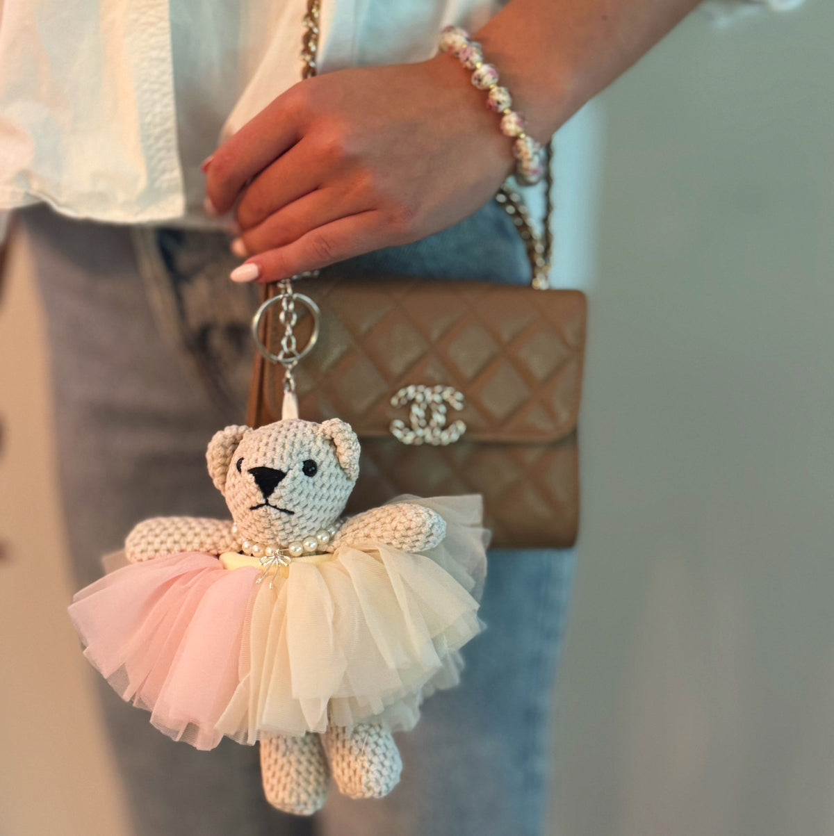 Crocheted bear bag charm with pink tutu skirt, pearl collar, and keychain ring