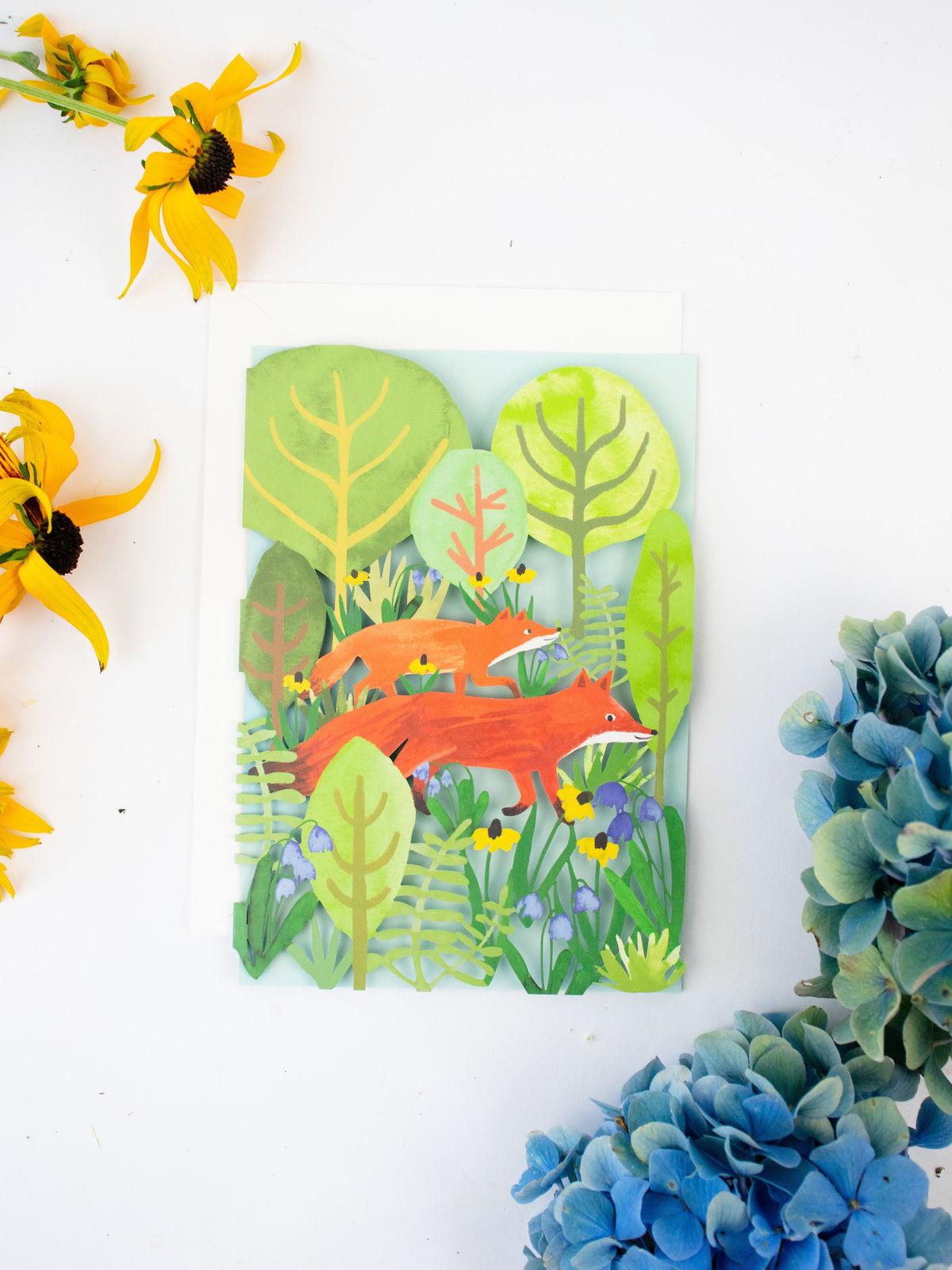Lasercut blank greeting card, flat view, forest cutout trees with red fox design