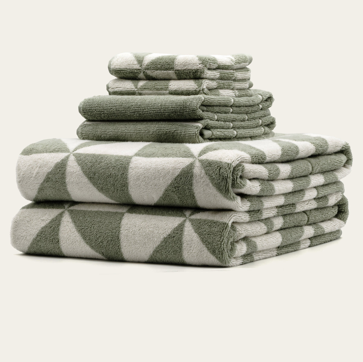 Stack of green and ecru geometric-check cotton towels with rolled layers visible