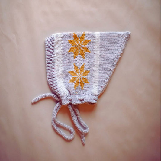 Knit pixie hat in light gray with orange star motifs and tied ear strings