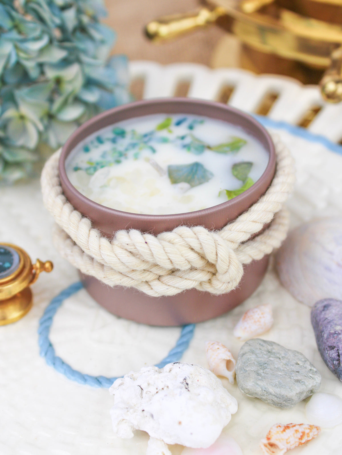 Botanical soy wax candle in rose-gold tin with cream rope bow and blue-green wax