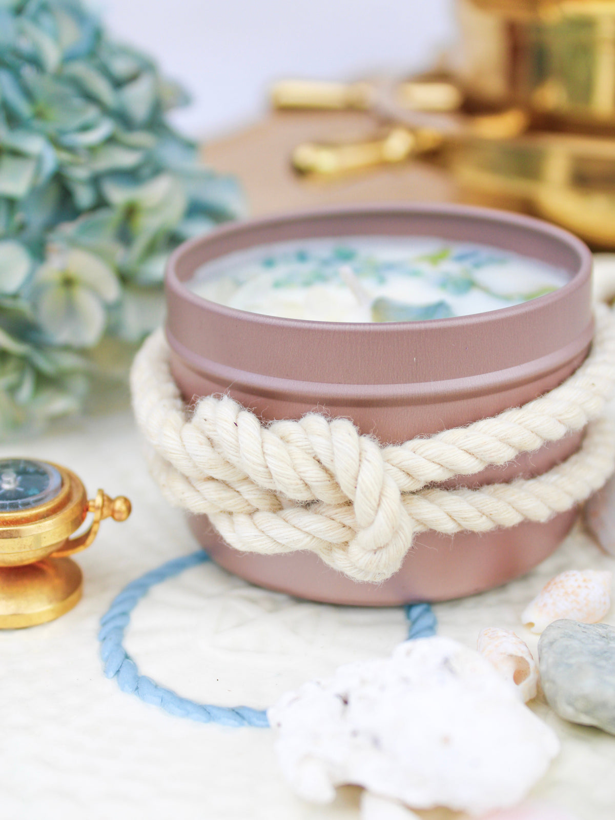 Botanical soy wax candle in rose-gold tin with cream rope bow and blue-green wax