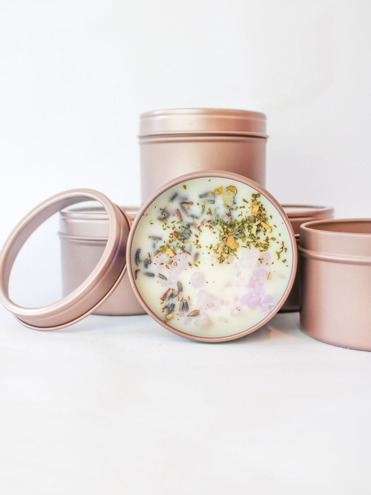 Botanical soy wax candle set in rose-pink tins; open top shows green herbs in white wax