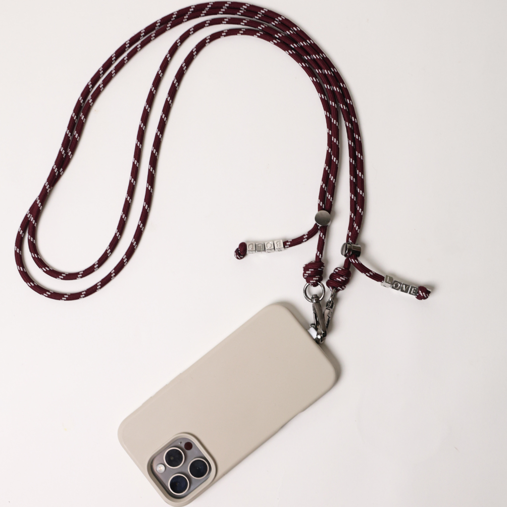 Burgundy striped phone strap with swivel clip and metal keyring, attached to phone case
