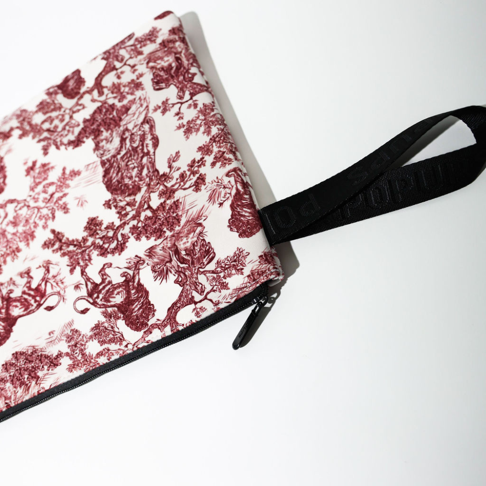 Close-up of maroon toile laptop sleeve corner with black zipper and strap