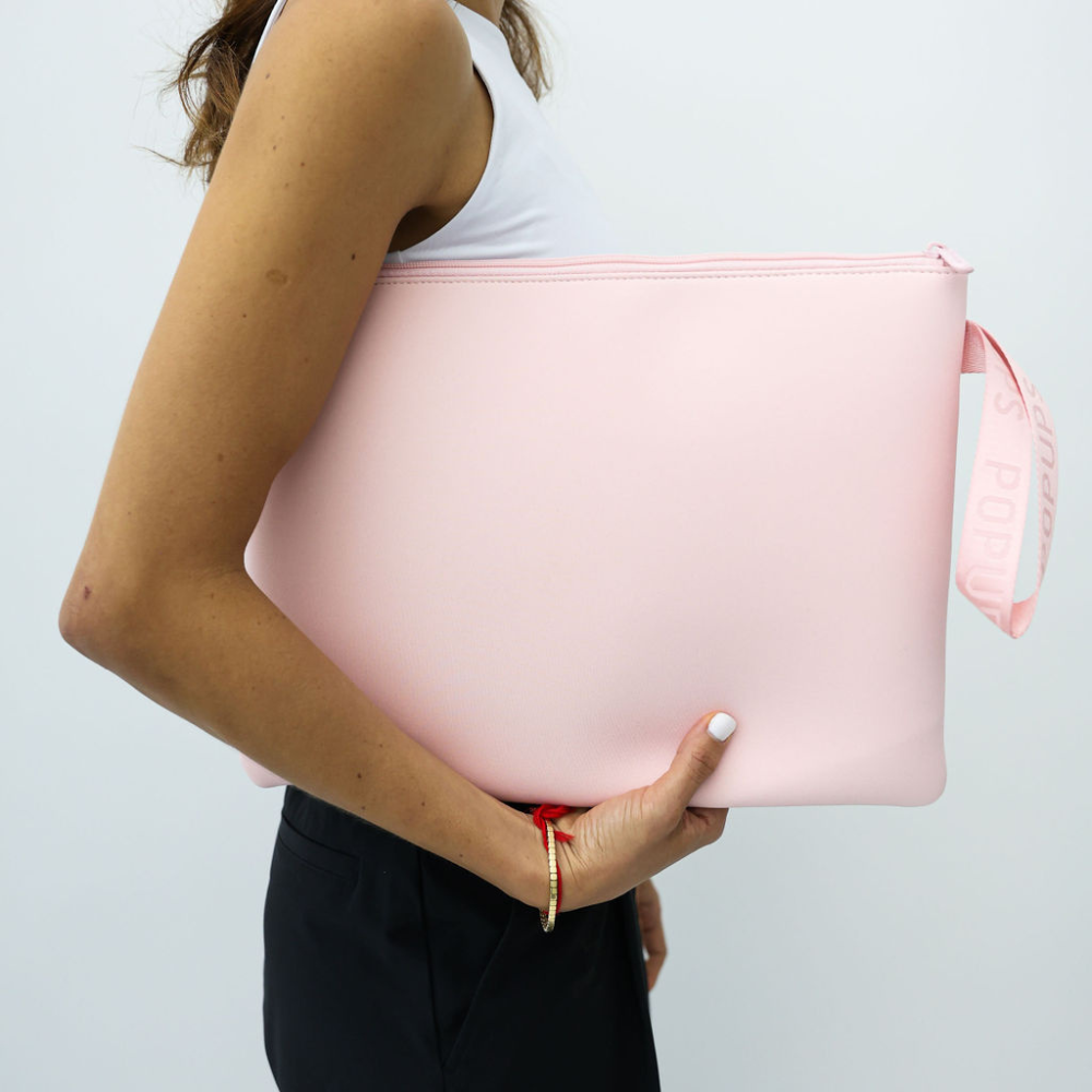 Pink laptop sleeve held by person, with zip top and ribbon wrist strap