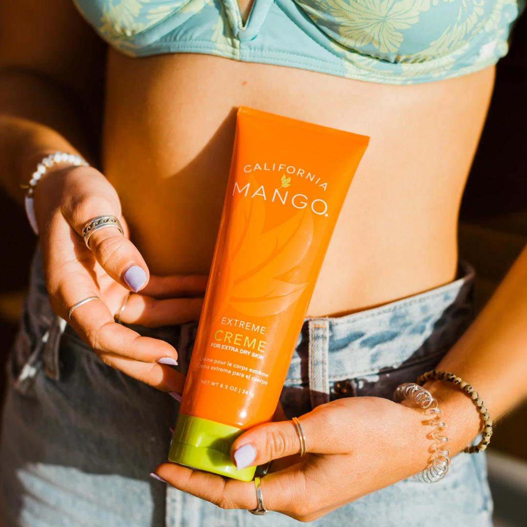 Orange squeeze cream tube with green base held in hands, 'California Mango' label