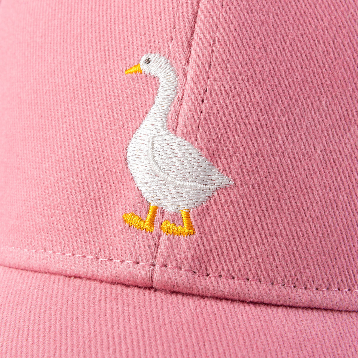 Embroidery detail: white goose with yellow feet on mauve pink cap, curved brim