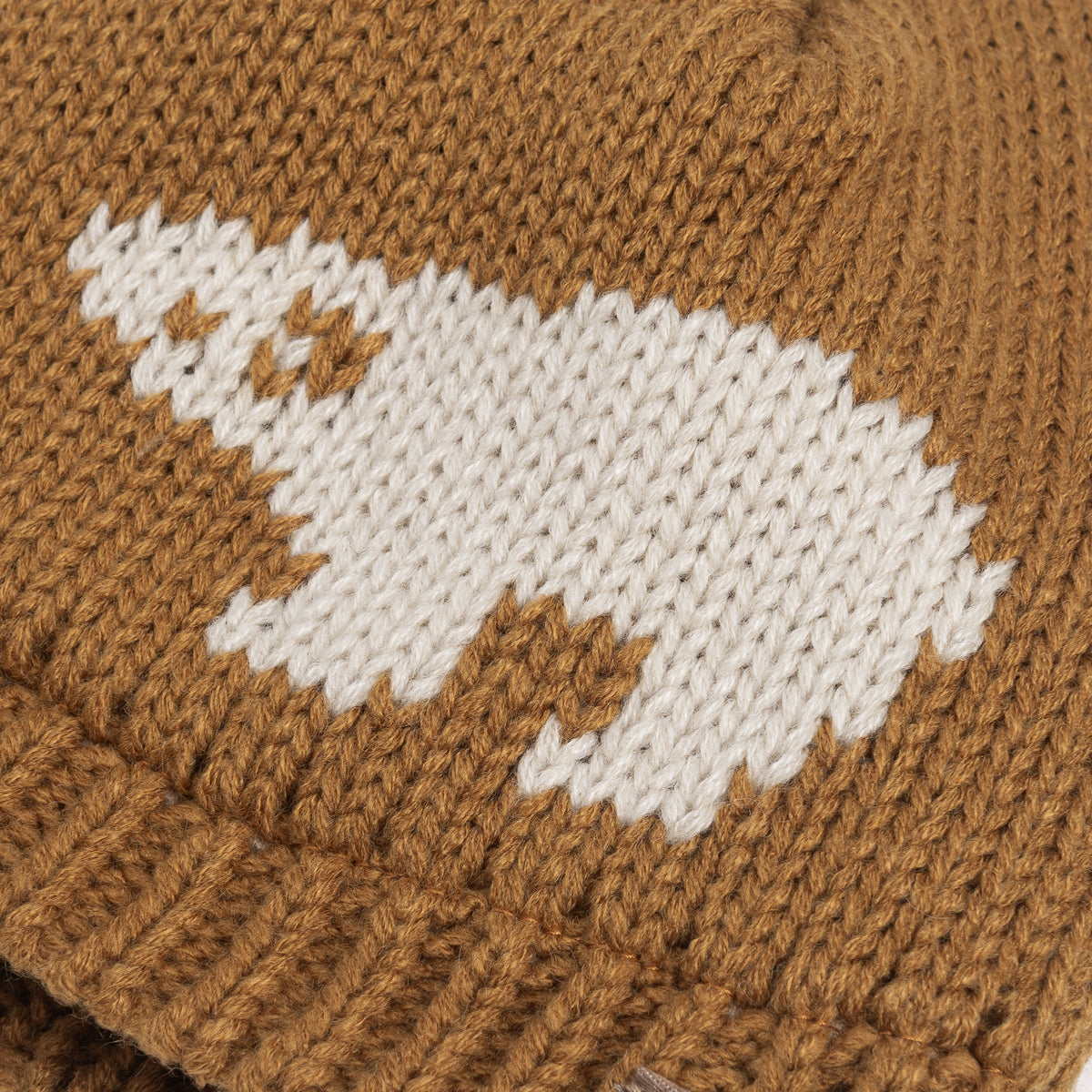 Close-up of the white bear motif knitted into the tan beanie