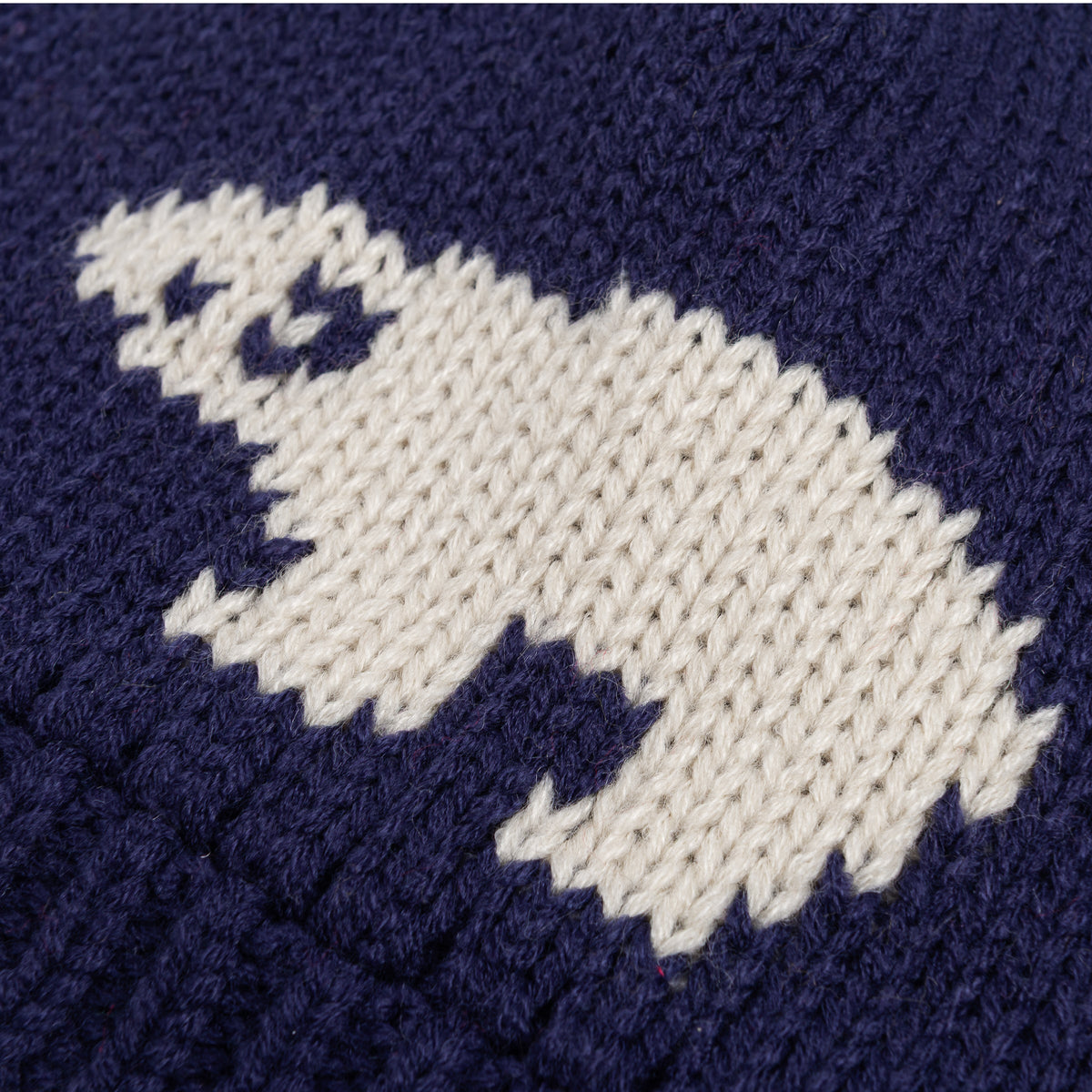 Close-up of the white bear motif knitted into the navy beanie