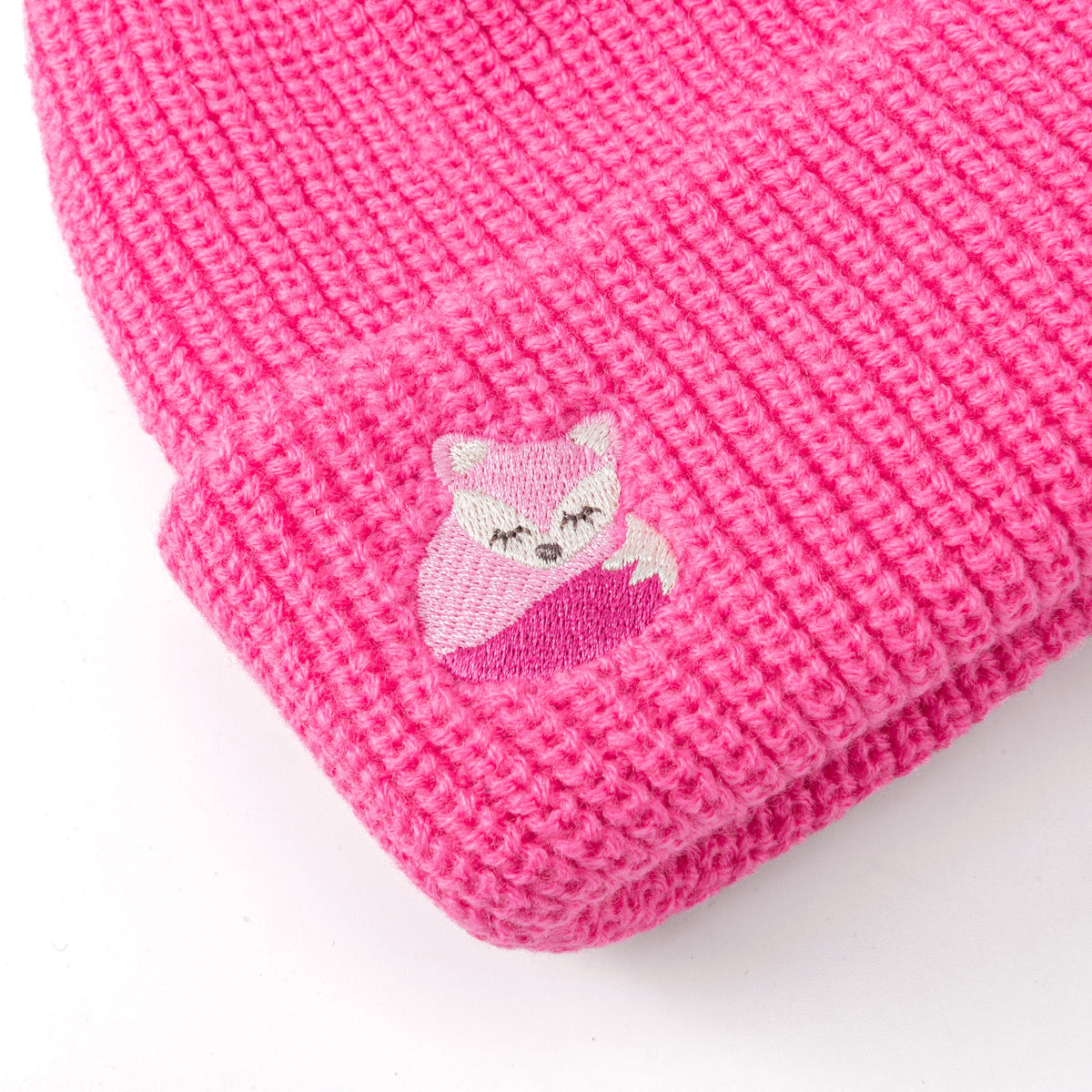 Close-up of the fox patch and knit texture on a bright pink beanie