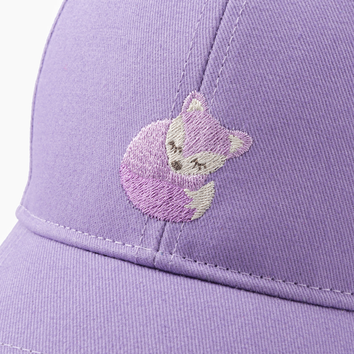 Close-up of the cap's embroidered fox patch on purple cotton fabric