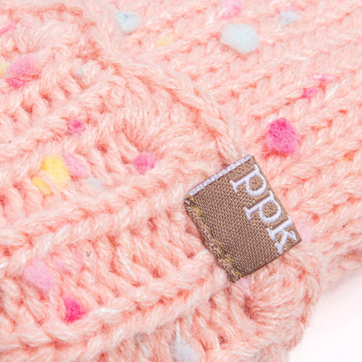 Close-up of pale pink speckled mitten knit and fabric brand tag