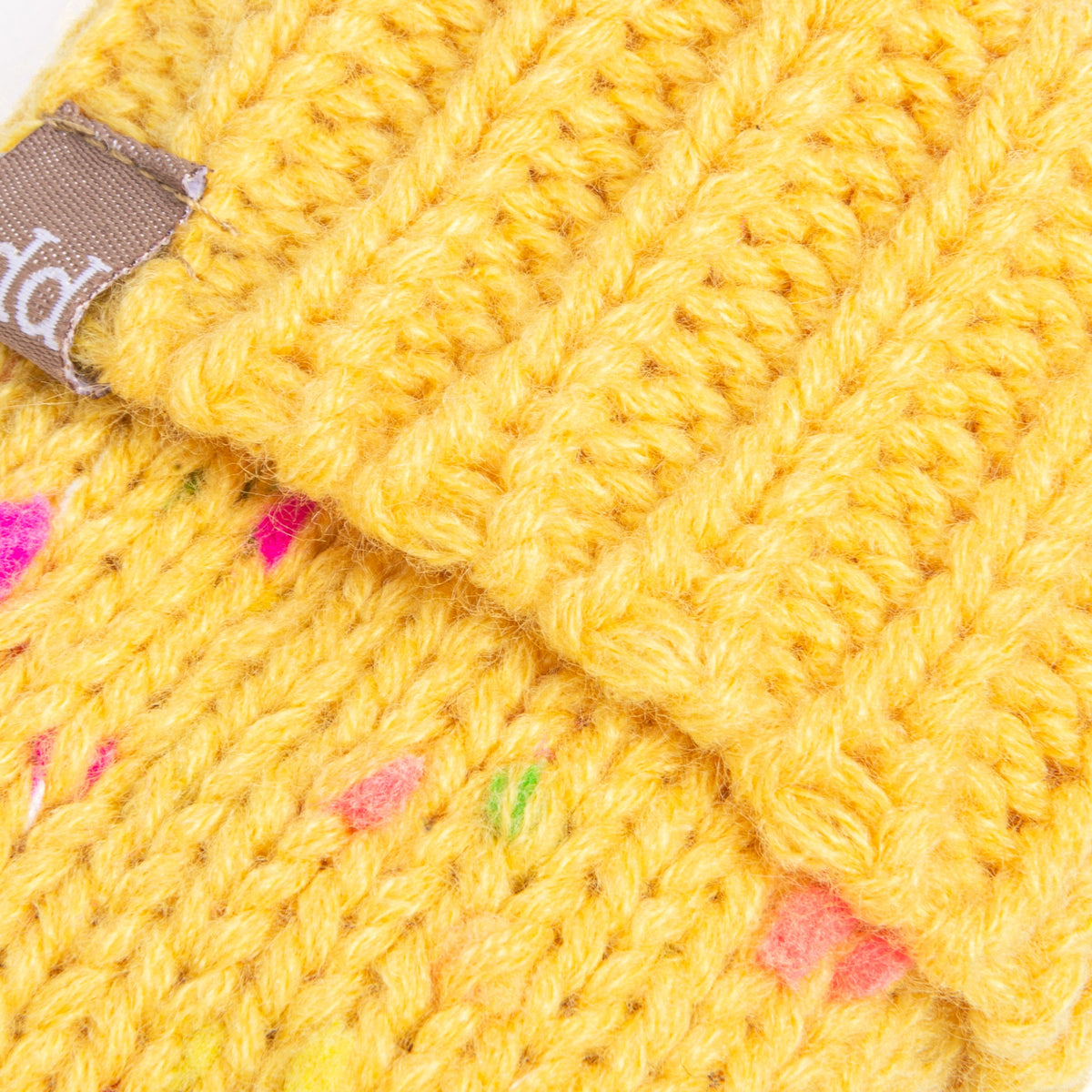 Close-up of yellow knit stitches, colorful flecks, and ribbed cuff