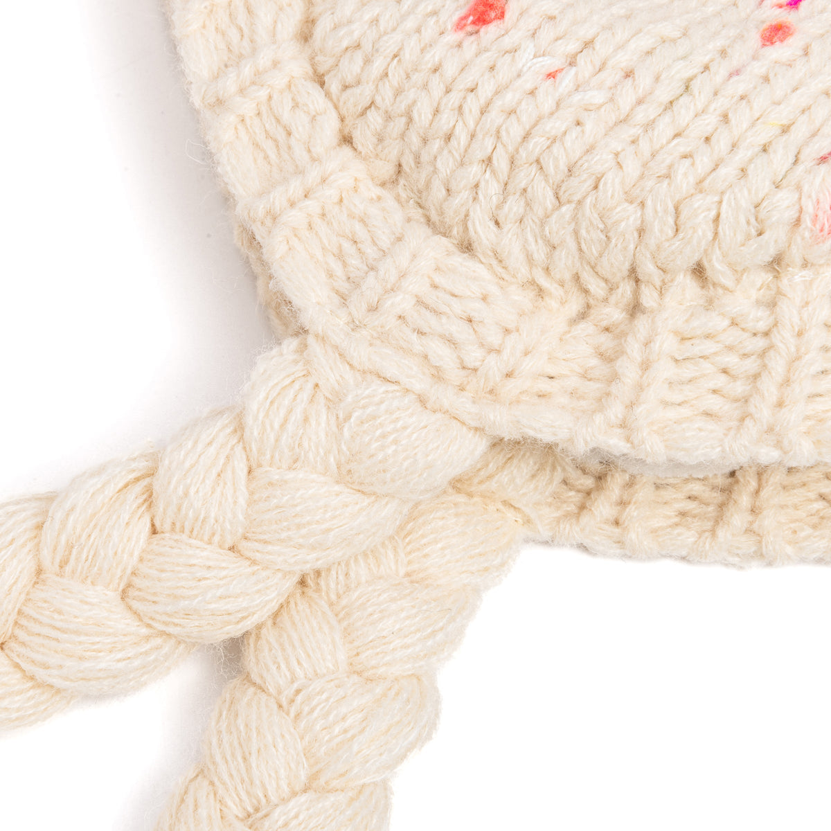 Close-up of cream knit earflap hat with braided ties and textured stitches