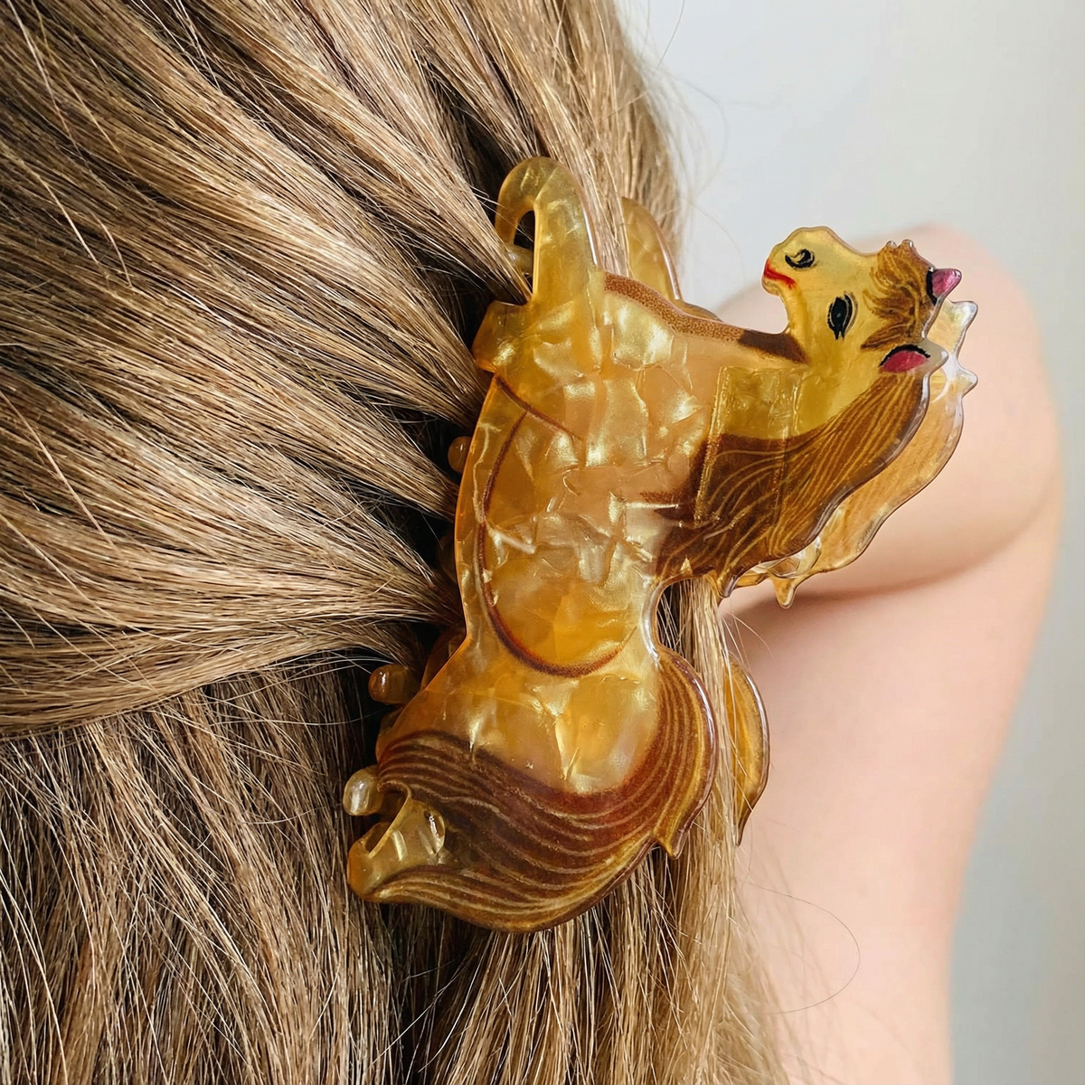 Glossy gold horse hair claw with red accents and curved claw teeth, close-up