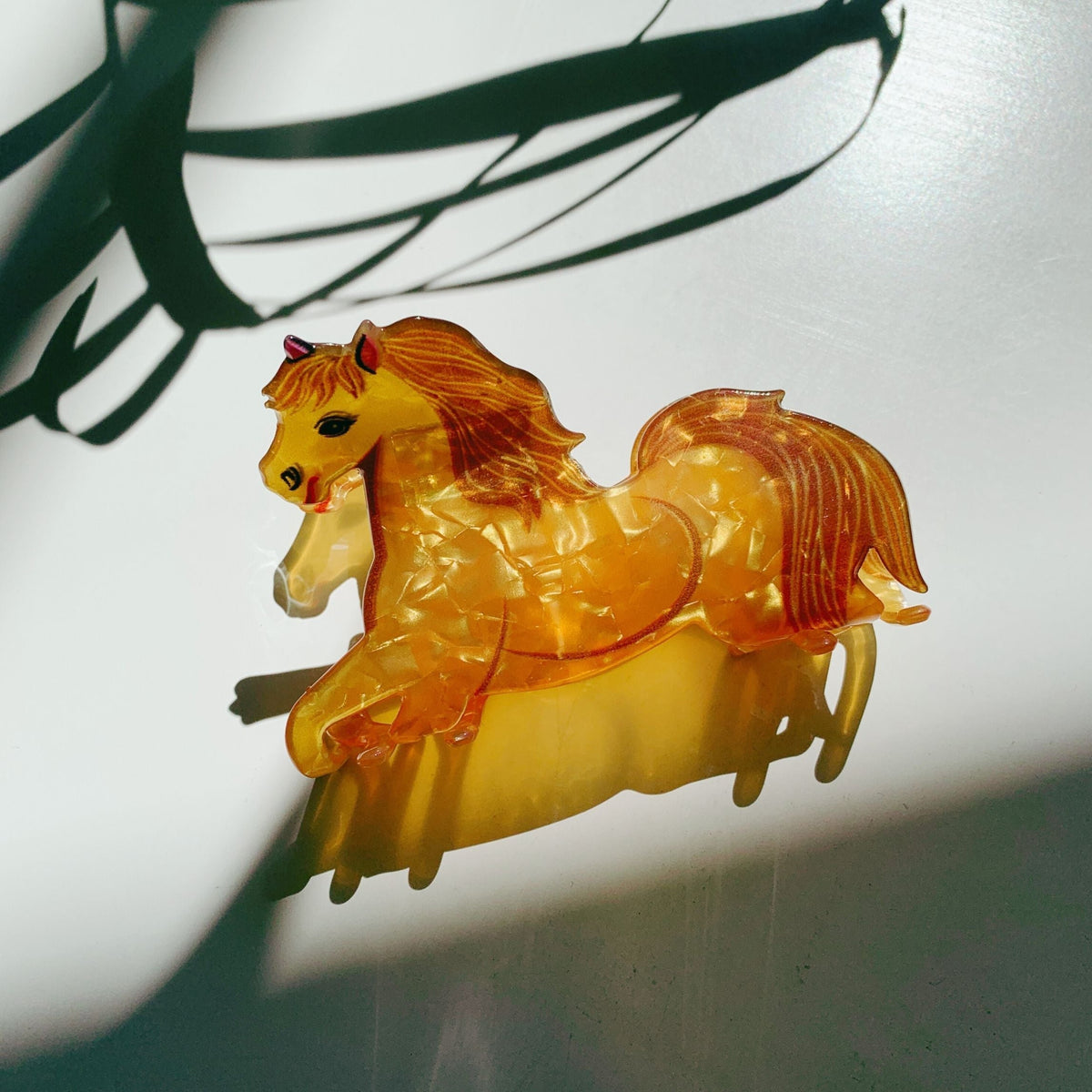 Gold horse motif hair claw with long mane, glossy finish and curved base