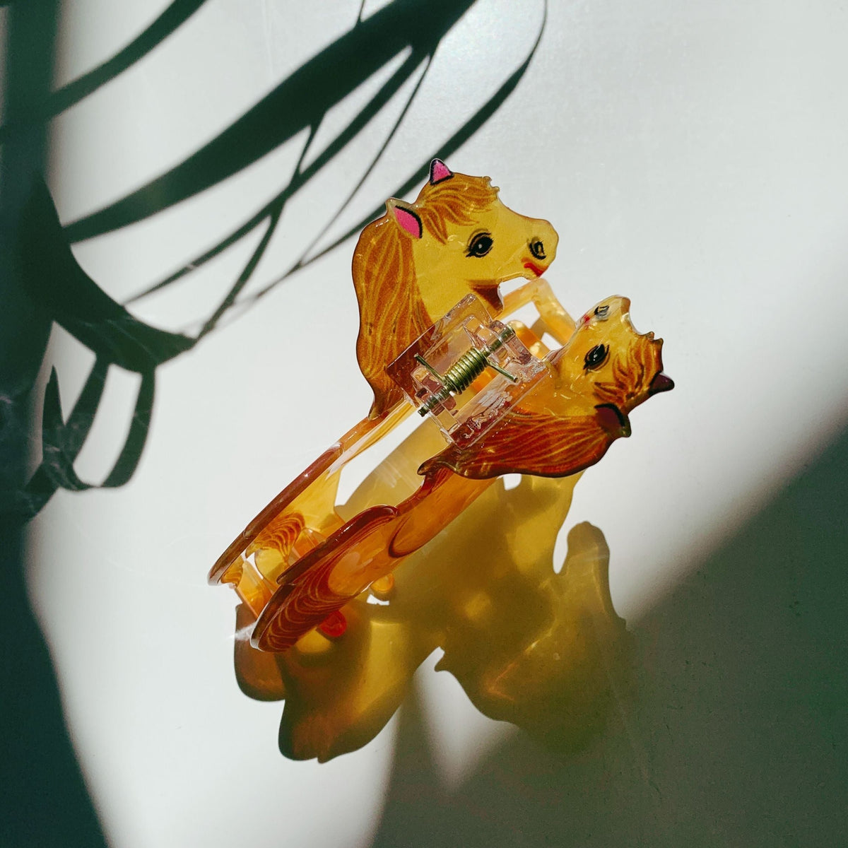 Gold horse hair claw featuring two horse figures and red mane accents