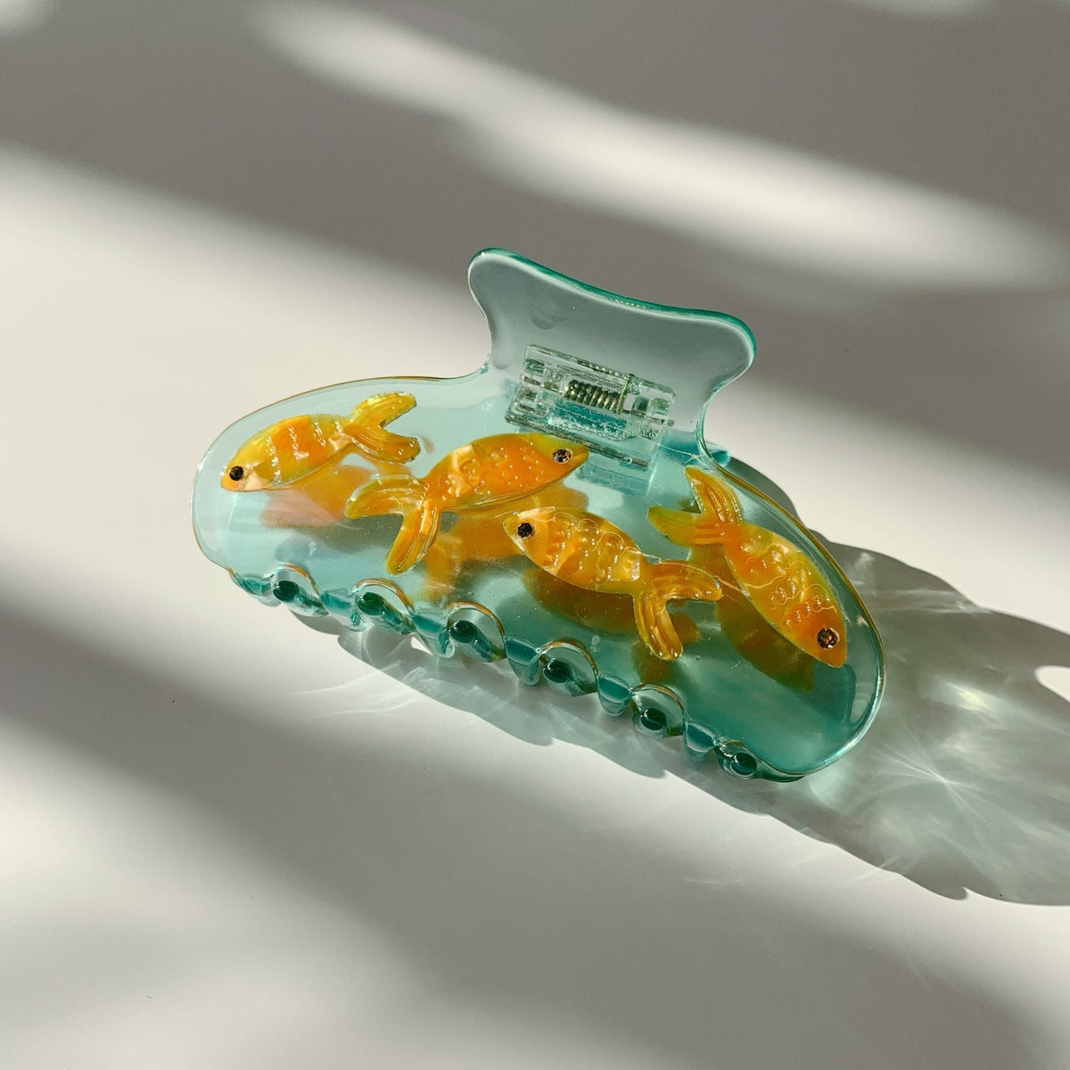Goldfish hair claw clip, angled view of teal transparent base with golden fish