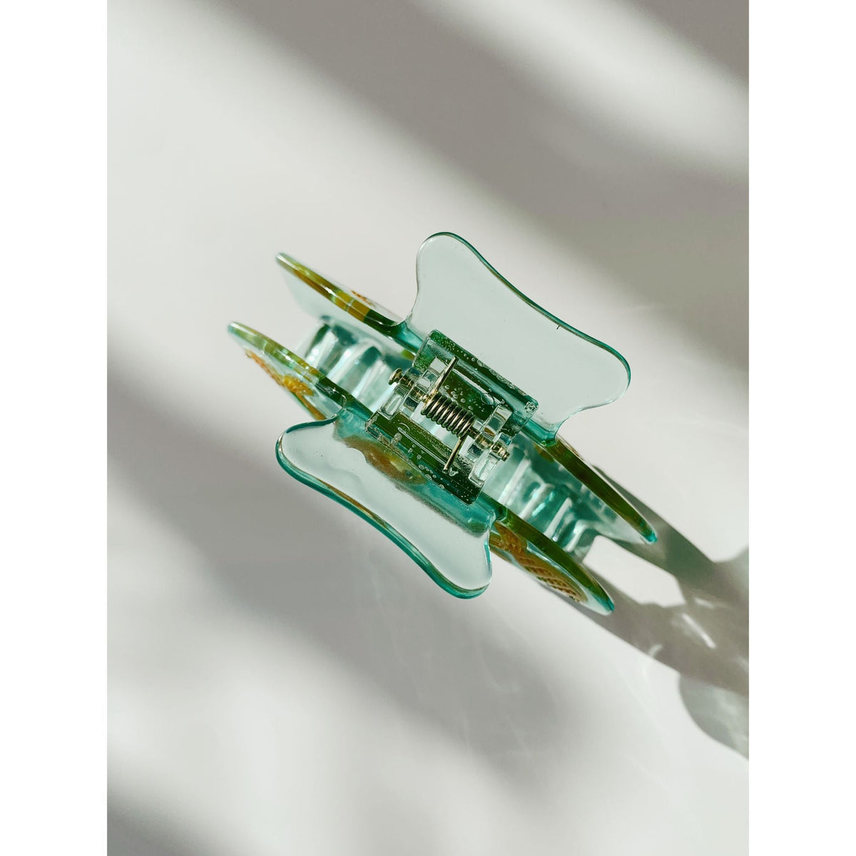 Goldfish hair claw clip, side view showing clear teal prongs and center hinge